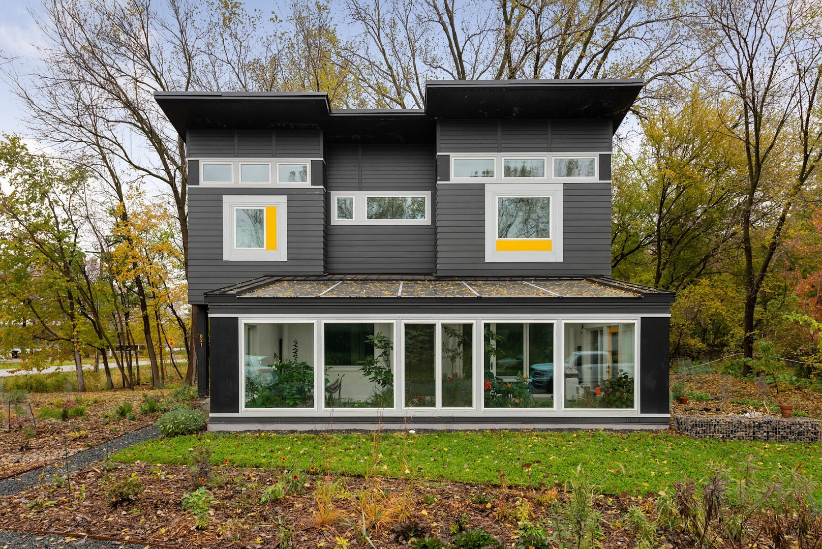 exterior of modern home with a greenhouse in the front during fall